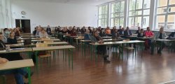Aula Instytutu Nauk Leśnych Politechniki Białostockiej w Hajnówce na której zgromadziło się kilkadziesiąt osób, które siedzą przy biurkach