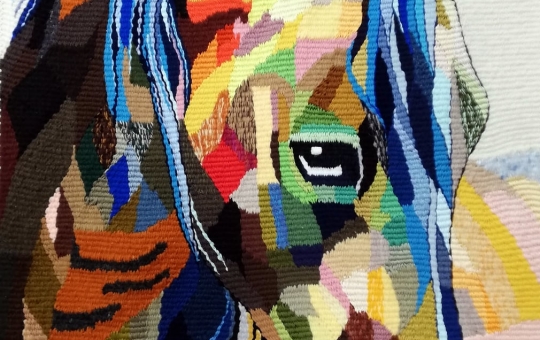 [zdjęcie przedstawia kolorową głowę konia wykonaną techniką gobelinu]